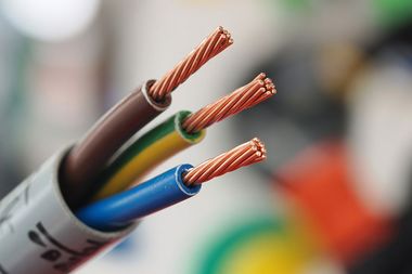 A close-up view of a multi-core electrical cable with three exposed, copper-stranded wires: brown, yellow-green, and blue.