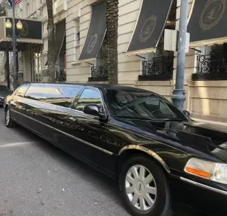 Black stretch limousine parked on a city street beside a building with awnings.