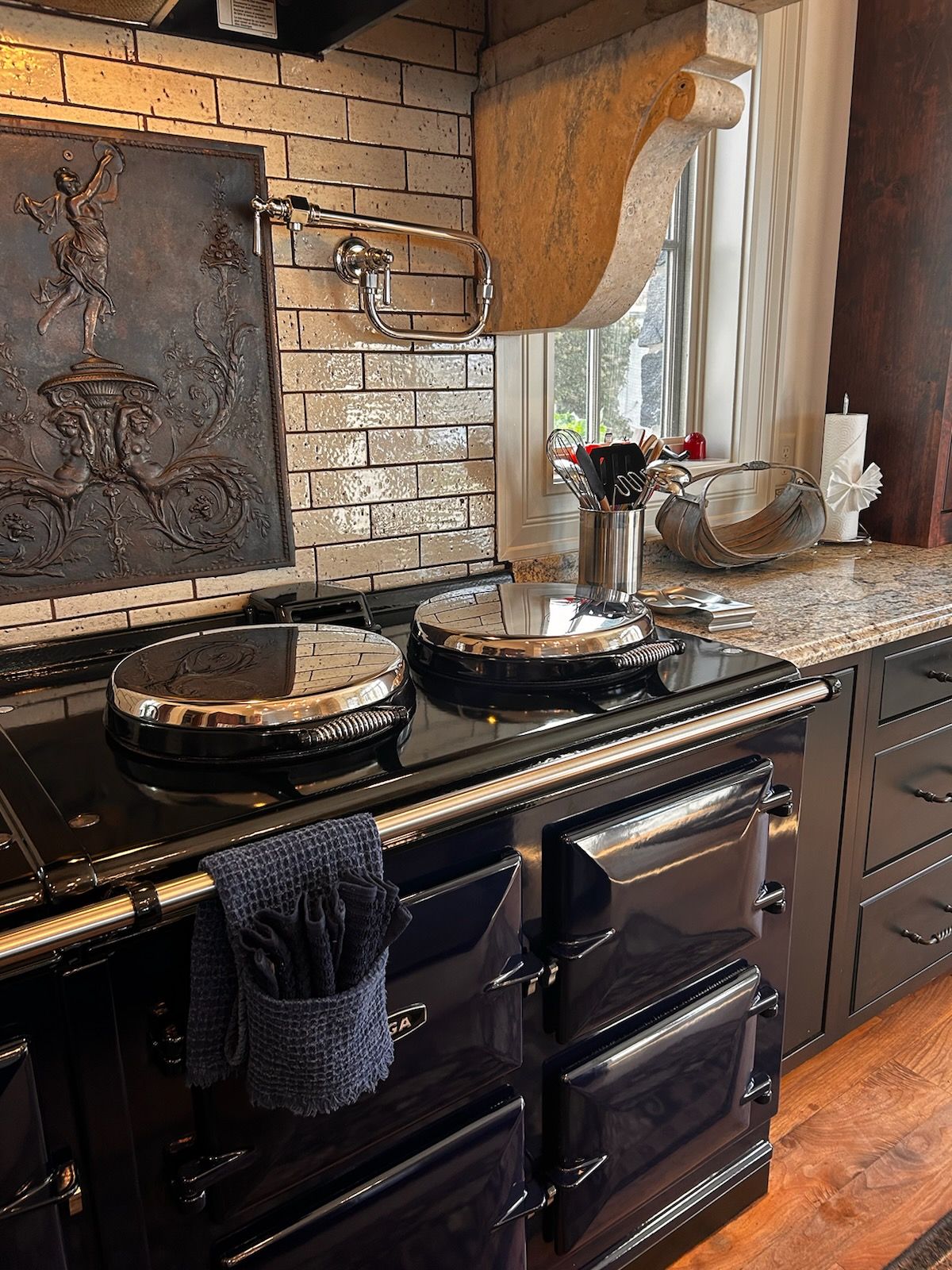 A black stove top oven is sitting in a kitchen next to a window.