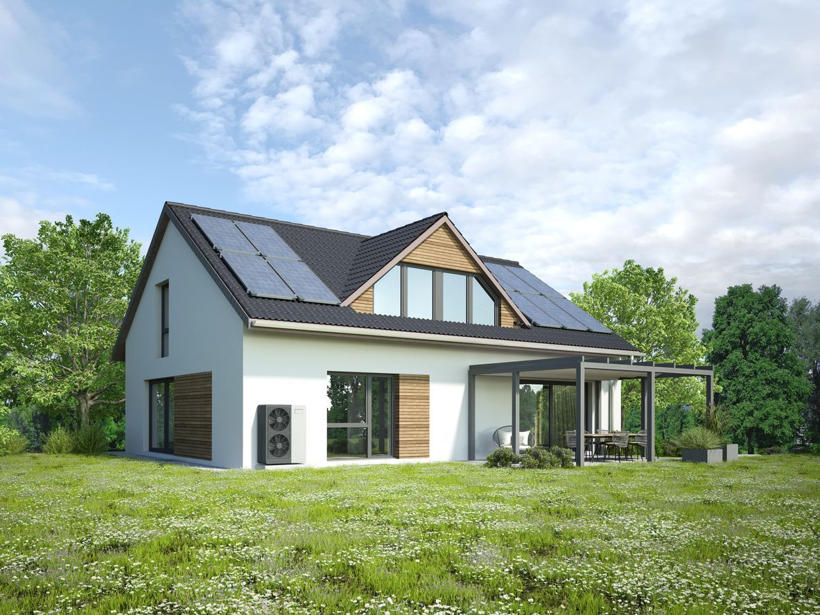 Modern house with solar panels on roof, surrounded by green grass and trees.