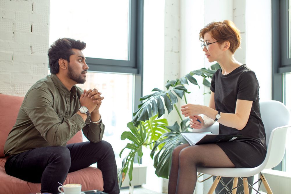A Person Sits on a Sofa, Looking at a Professional Who is Taking Notes — PoDDSS in Brisbane, QLD