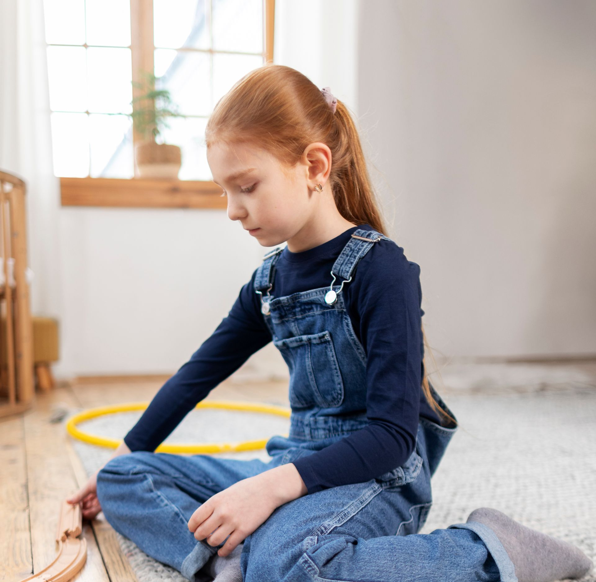 A Person With Long Hair in Denim Overalls Sits on a Carpeted Floor — PoDDSS in Ayr, QLD