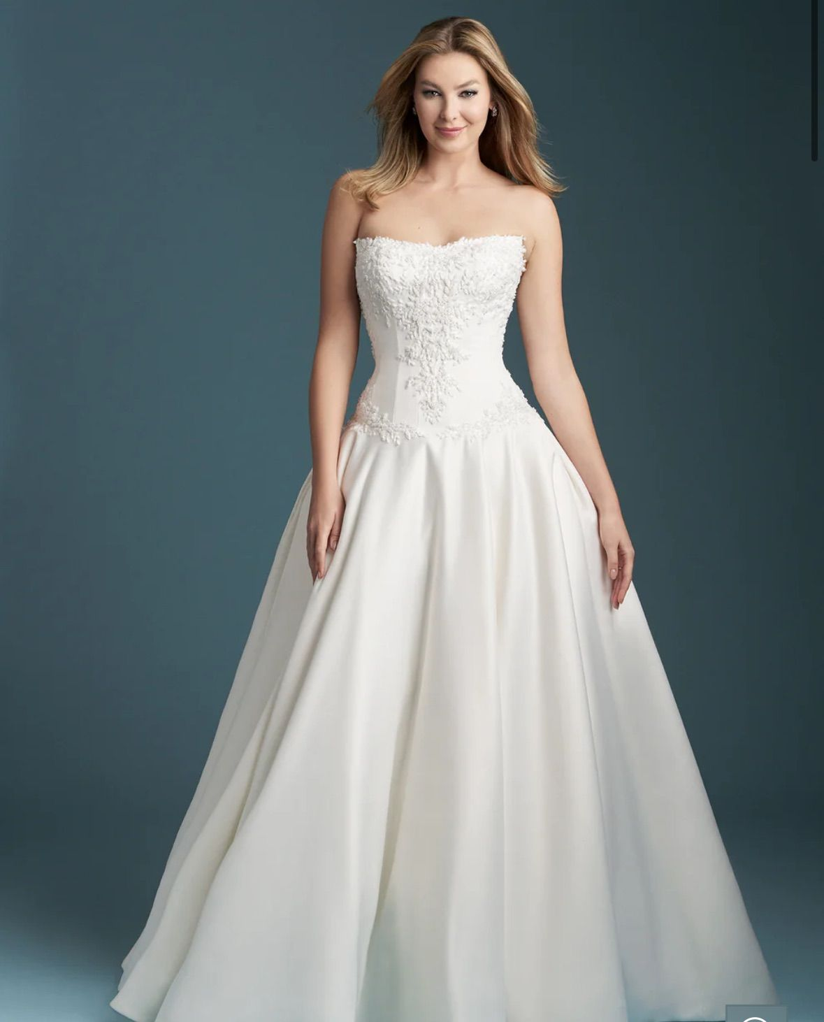 A woman in a wedding dress is standing in a field holding a bouquet of flowers.