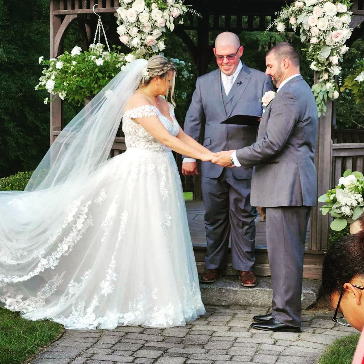 A bride and groom hold hands during their wedding ceremony