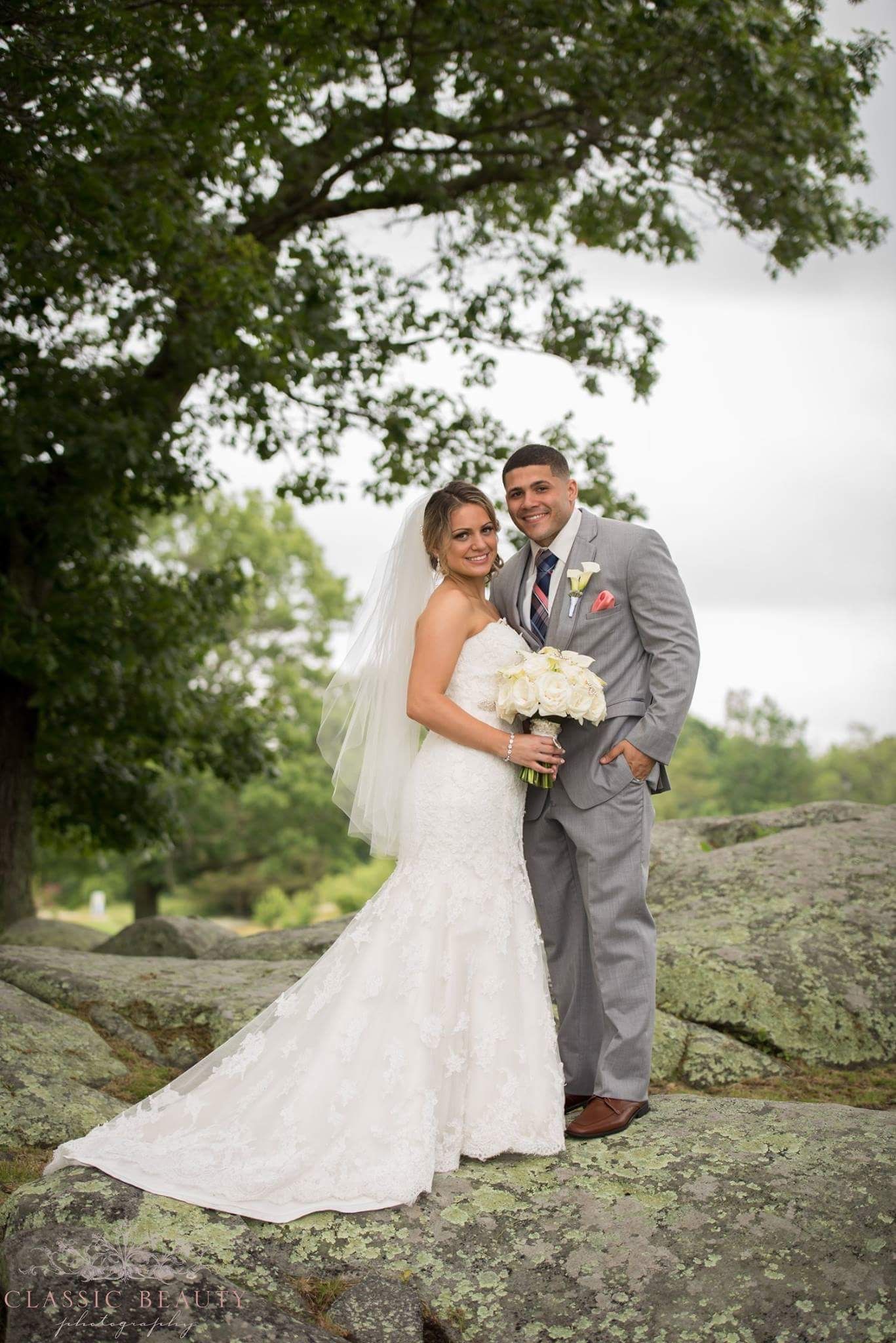 A bride and groom are posing for a picture on a rock.