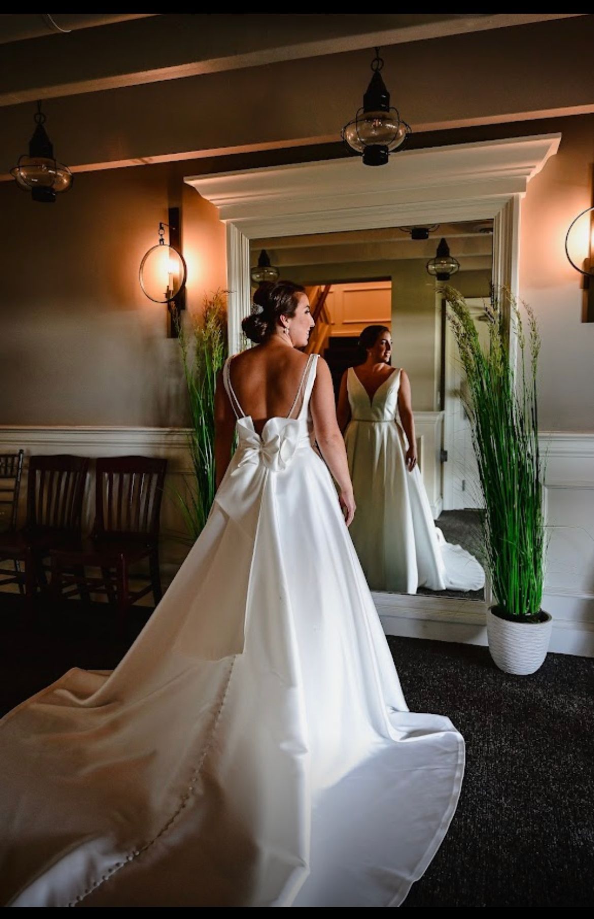 A woman in a wedding dress is standing in front of a mirror.
