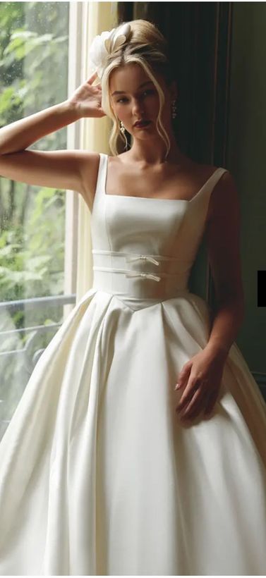 A woman in a wedding dress and veil is standing in front of a picture.