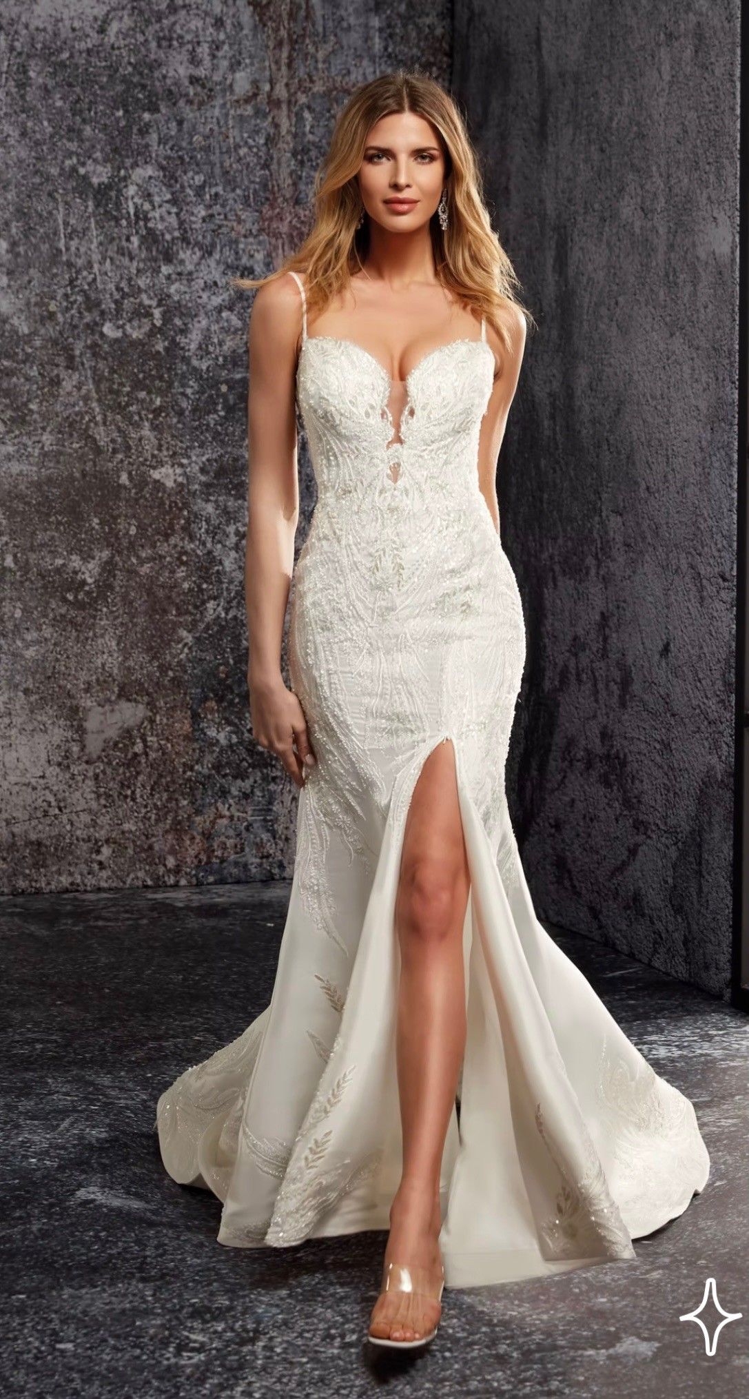 A model in a floor-length, embellished white bridal gown with a sweetheart neckline and a high front slit.