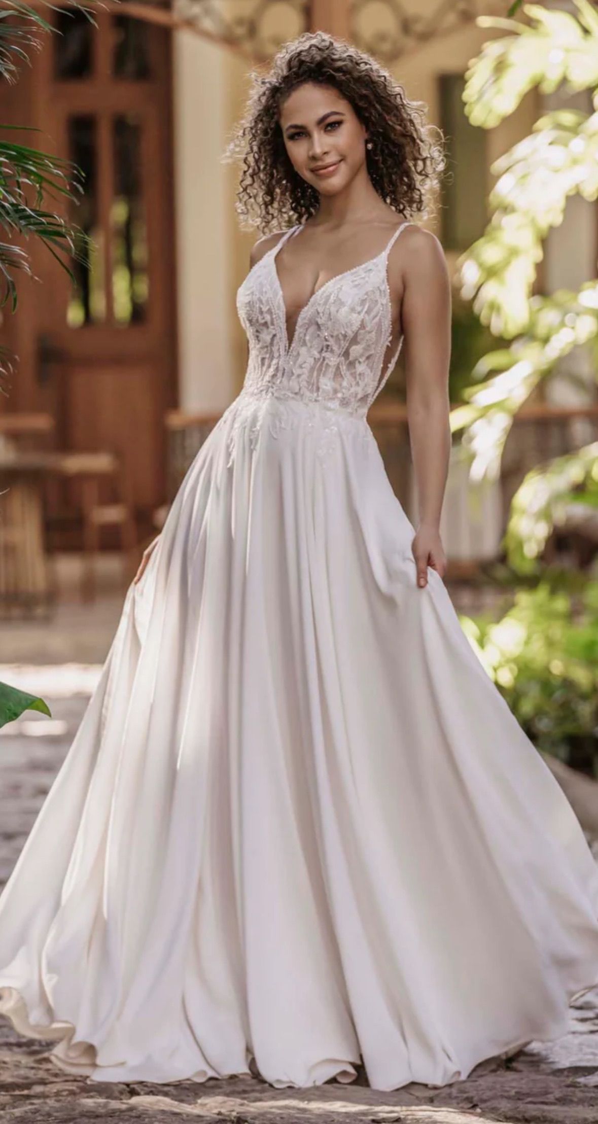 Bride in a flowing ivory wedding dress with lace bodice, outdoors.