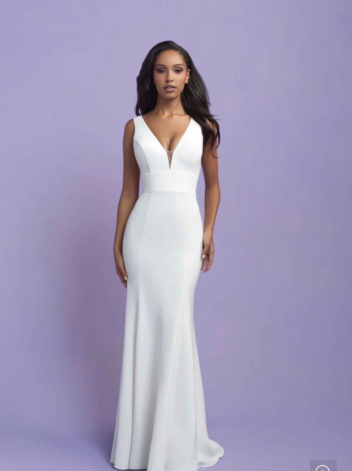 Woman in white wedding dress with plunging neckline, standing on lavender background.
