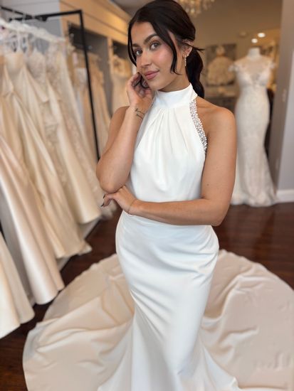 A woman is wearing a white wedding dress in a bridal shop.