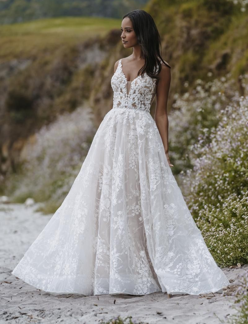 Woman in a white lace wedding dress, standing outdoors.