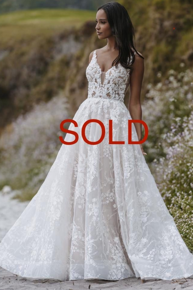 Woman in a white lace wedding dress, standing outdoors.