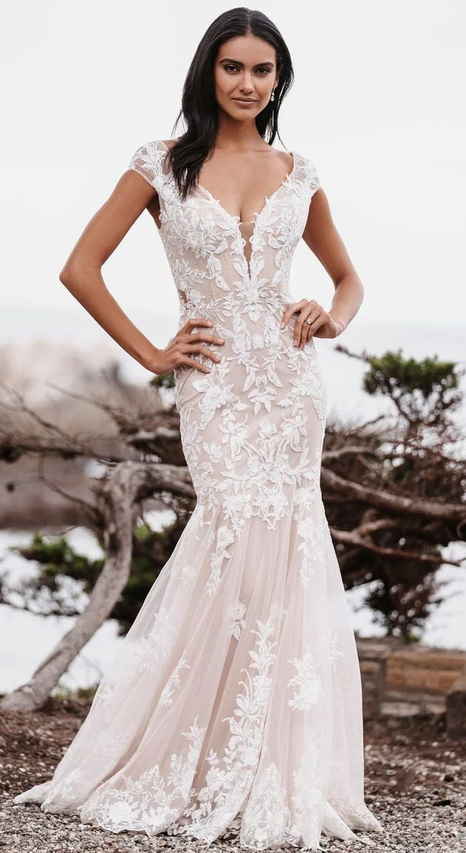 A woman is wearing a white lace wedding dress with short sleeves.