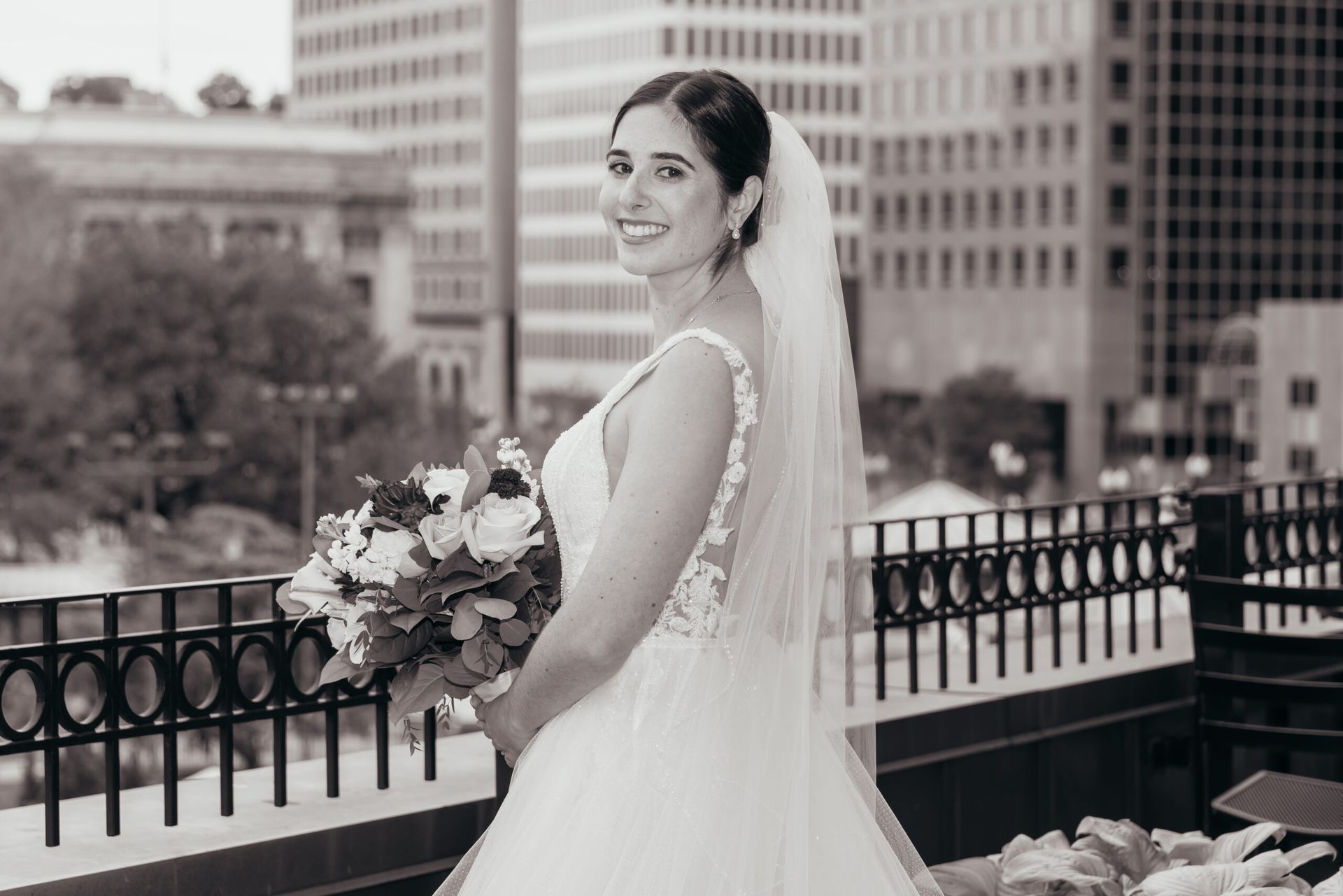 A black and white photo of a bride in a wedding dress holding a bouquet of flowers.