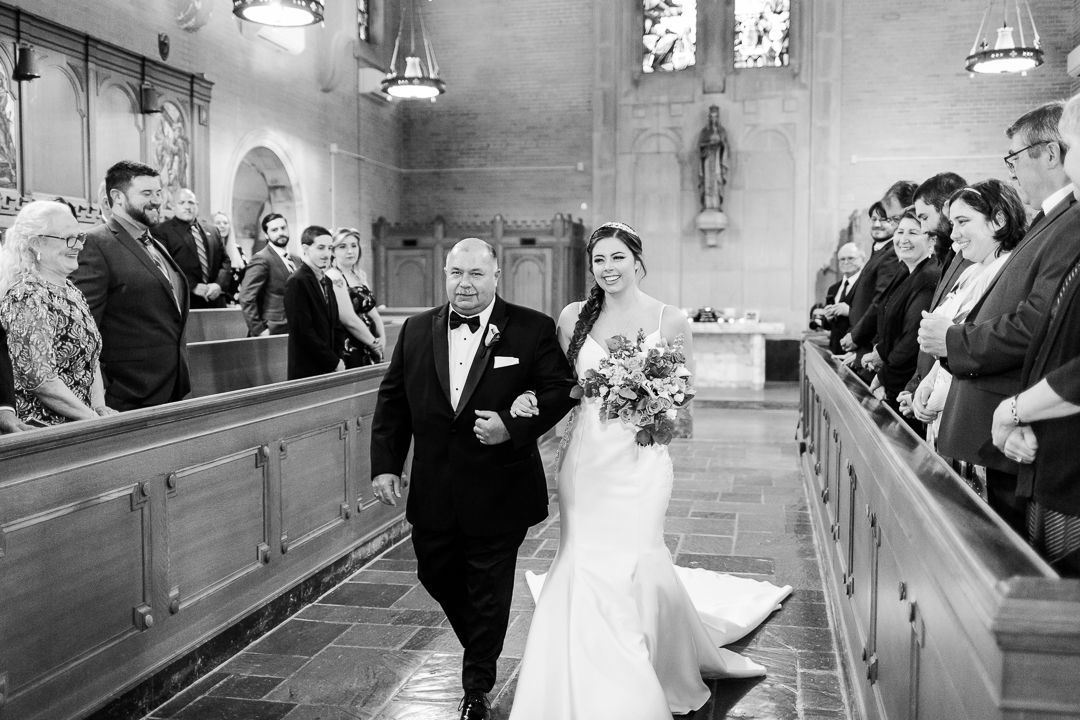 A bride and her father are walking down the aisle of a church.