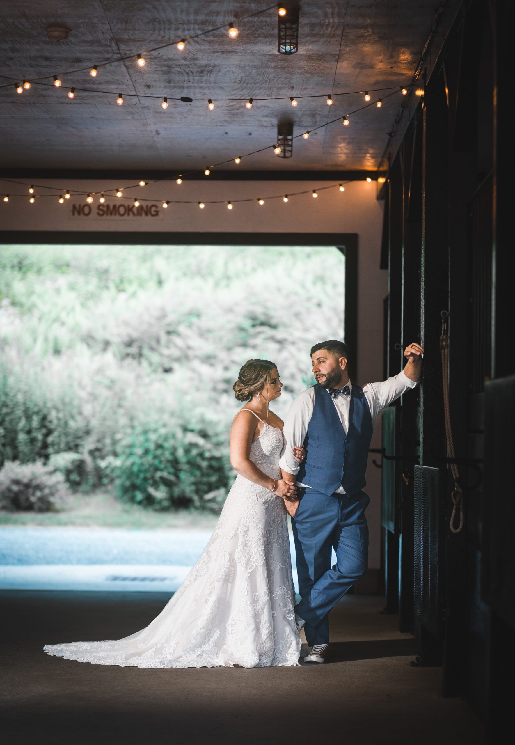 A bride and groom are standing next to each other in a barn holding hands.