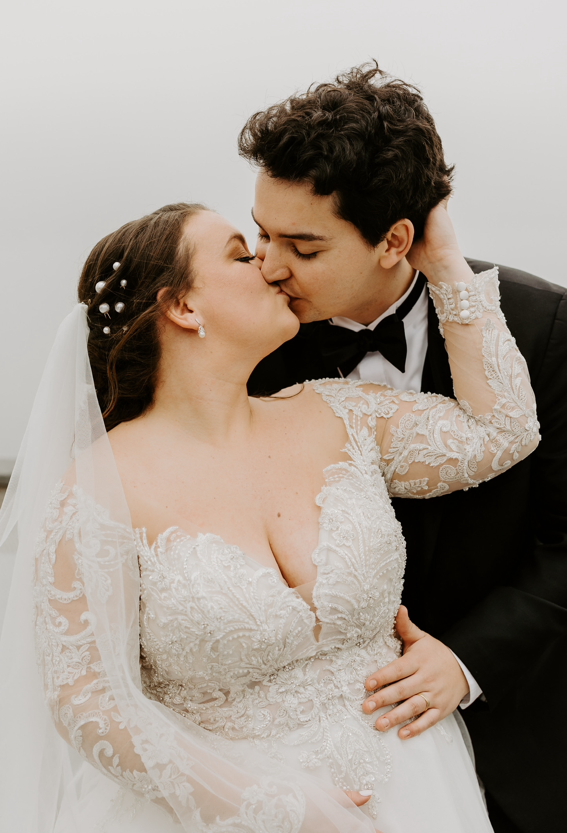 A bride and groom are kissing on their wedding day.