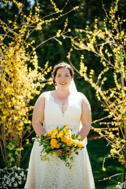A bride in a white dress is holding a bouquet of yellow flowers.