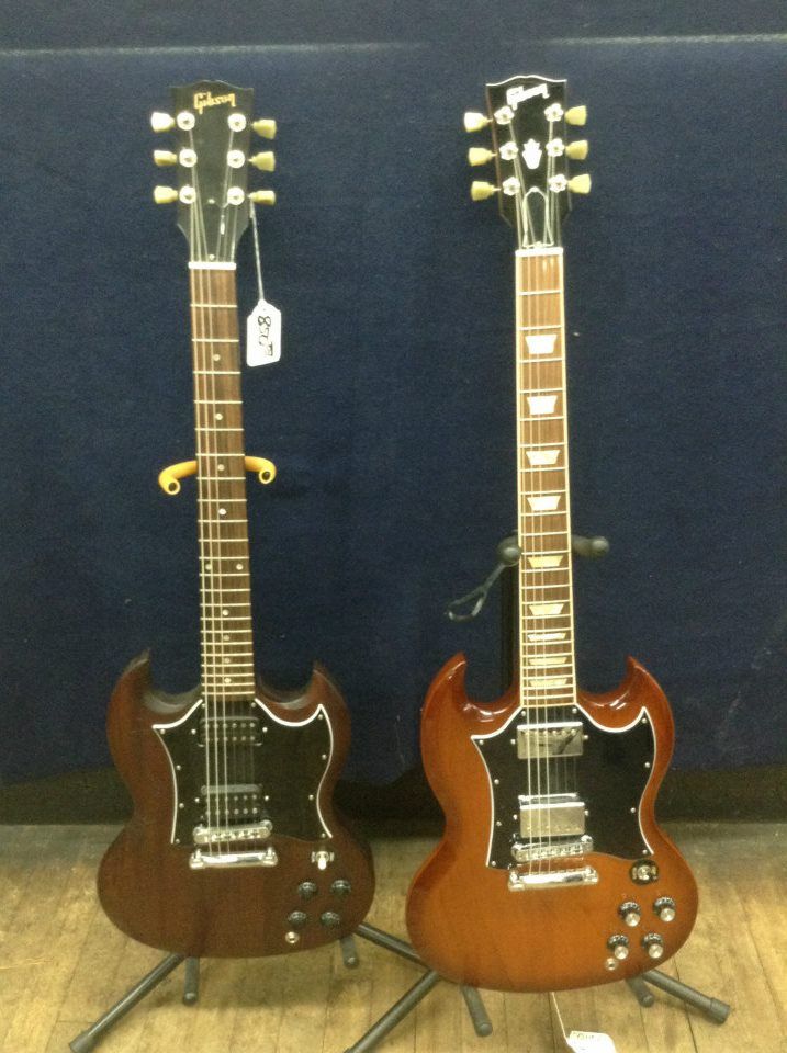 Two gibson guitars are sitting next to each other