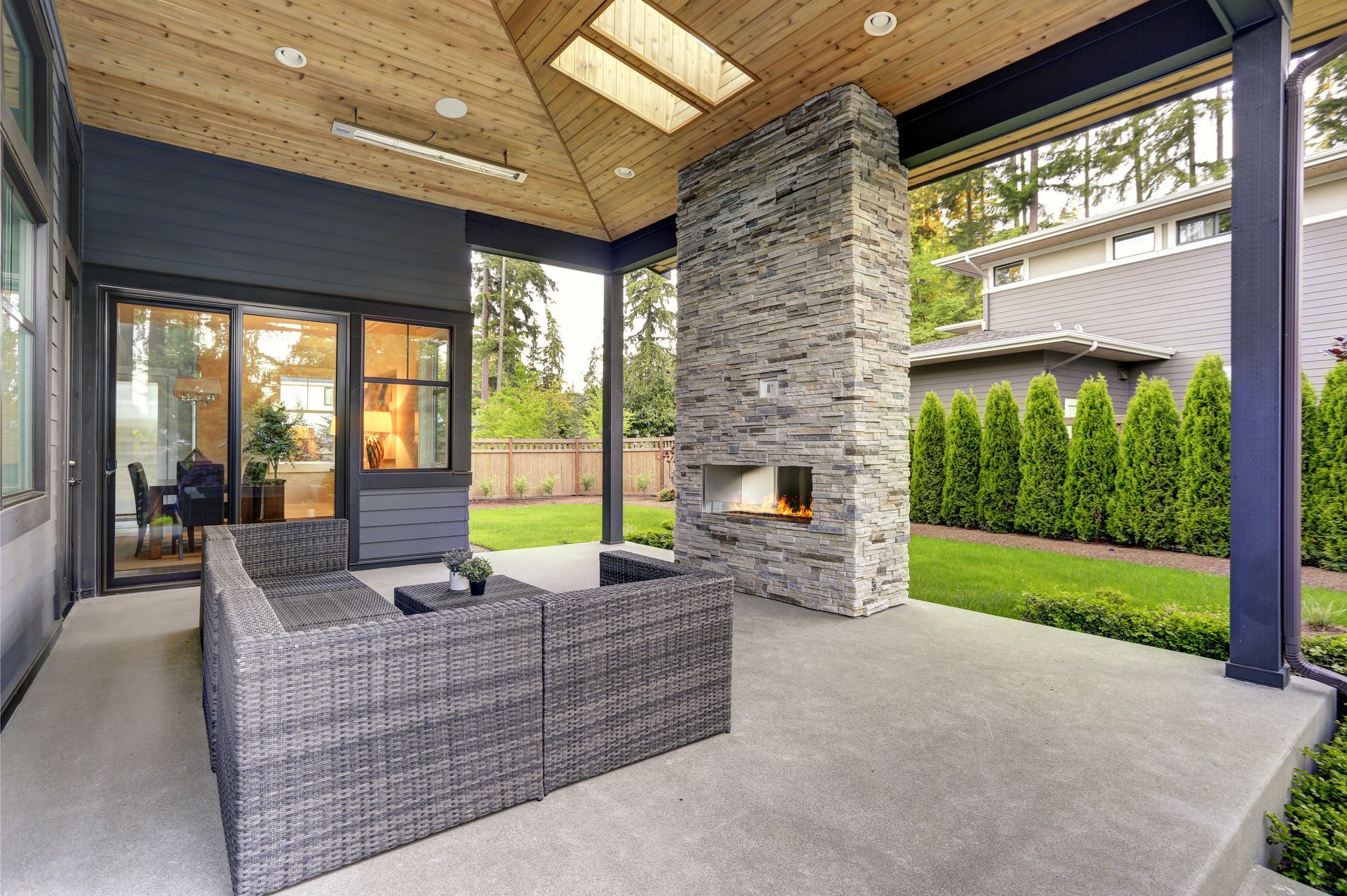 A large covered patio with a fireplace and a couch.