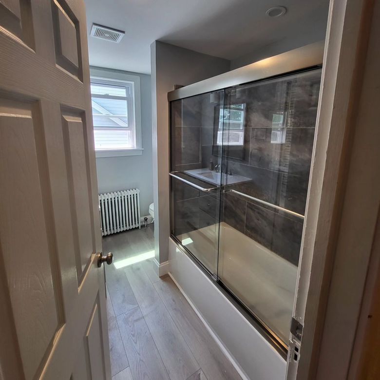 A bathroom with a glass shower door and a sink.