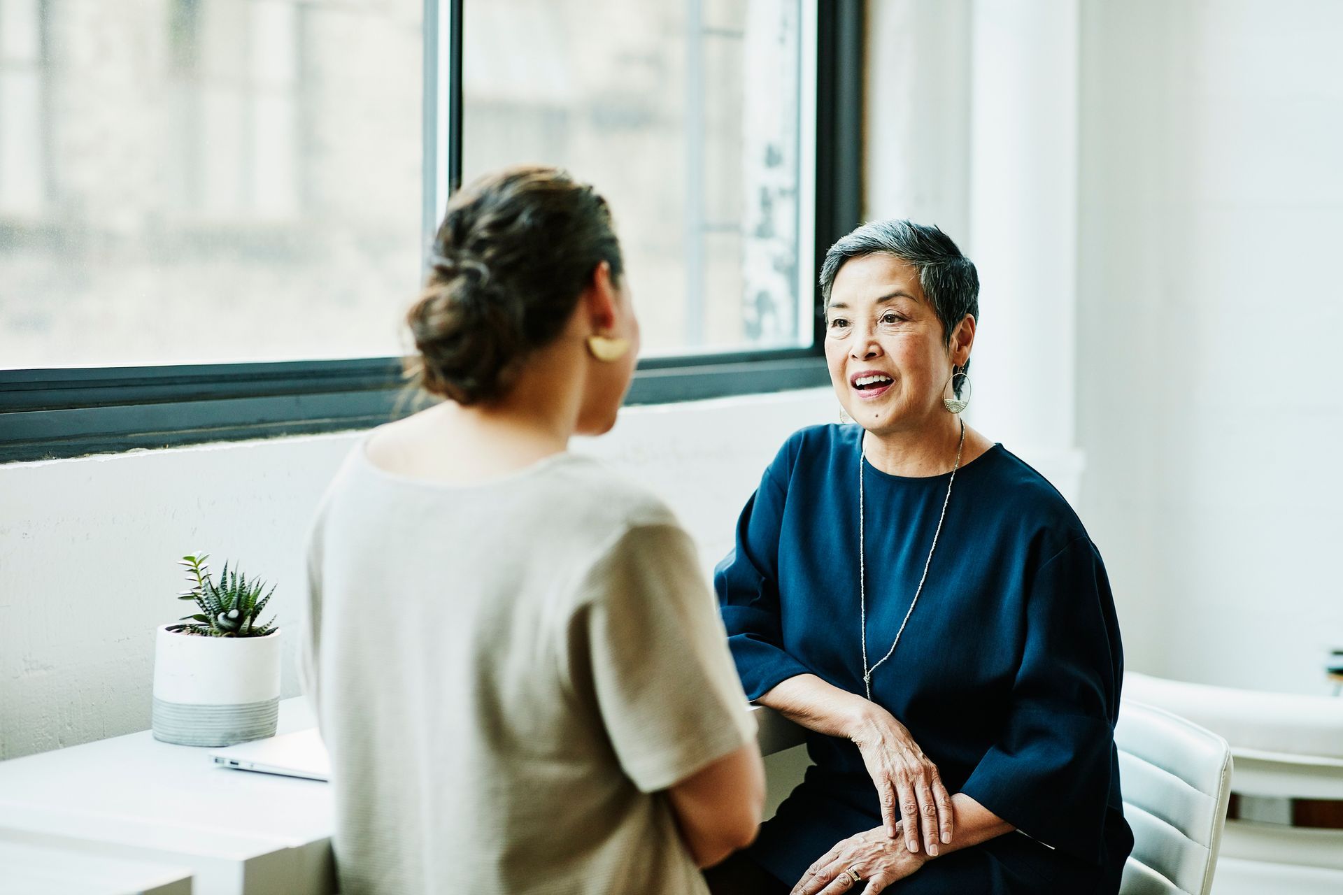 Two women are sitting at a table talking to each other.