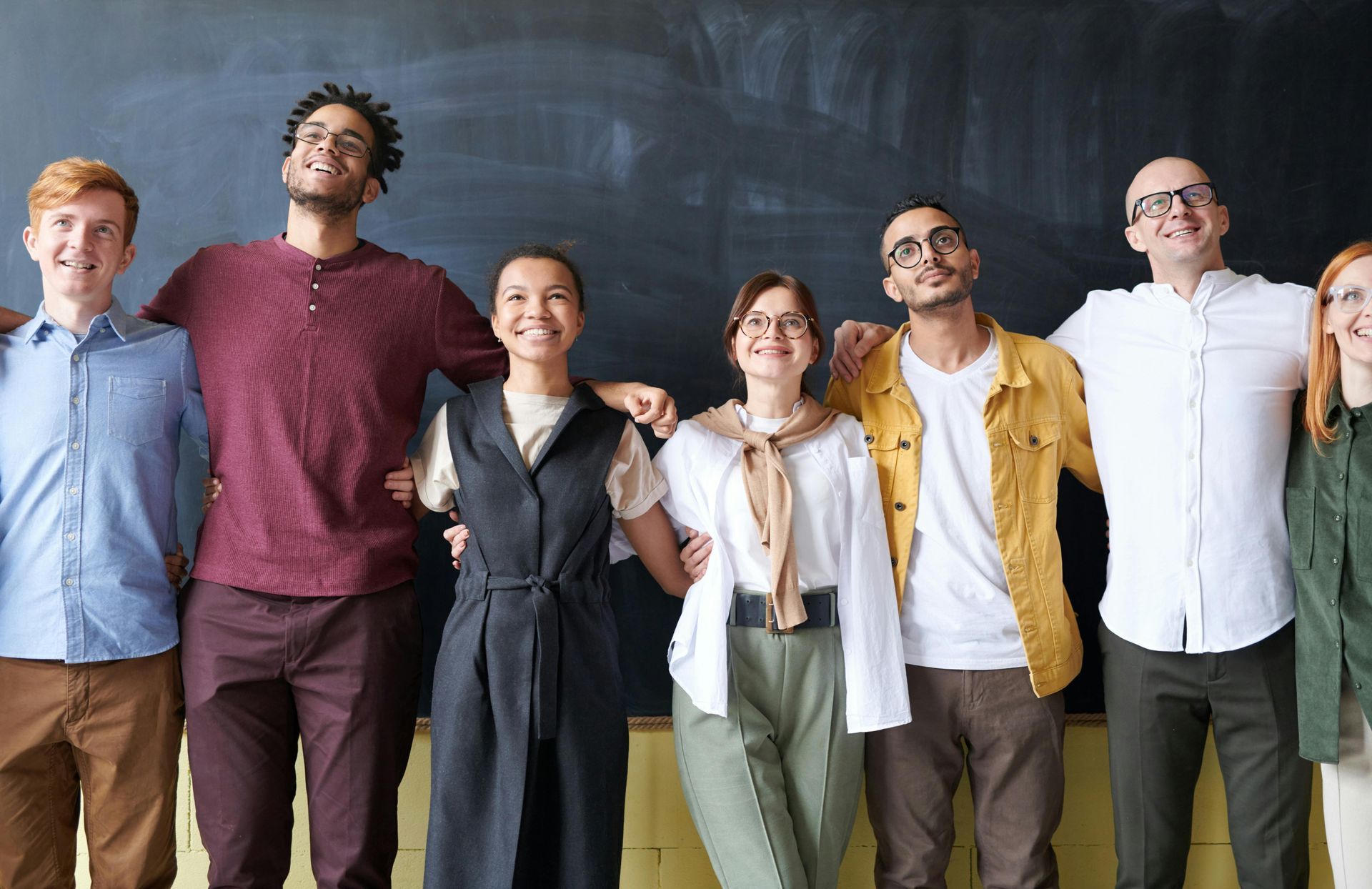 A group of people are standing next to each other in front of a blackboard.