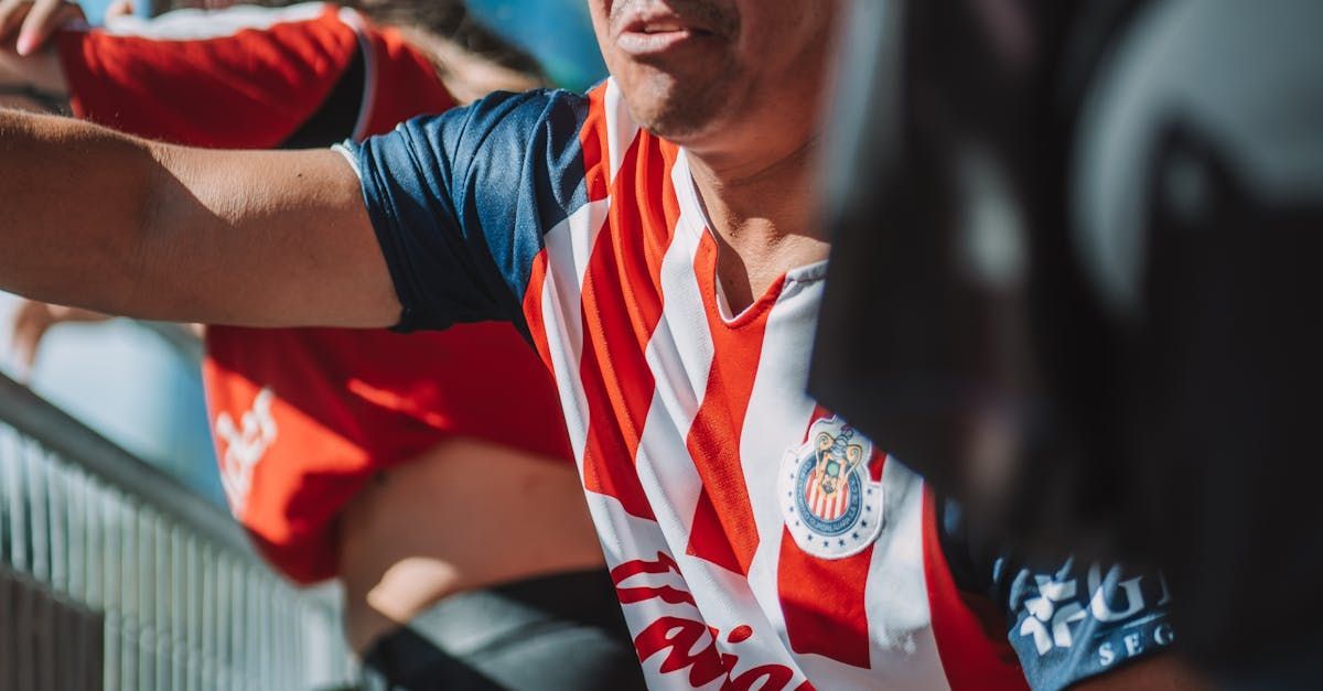 A man in a red and white striped shirt is sitting in a stadium.