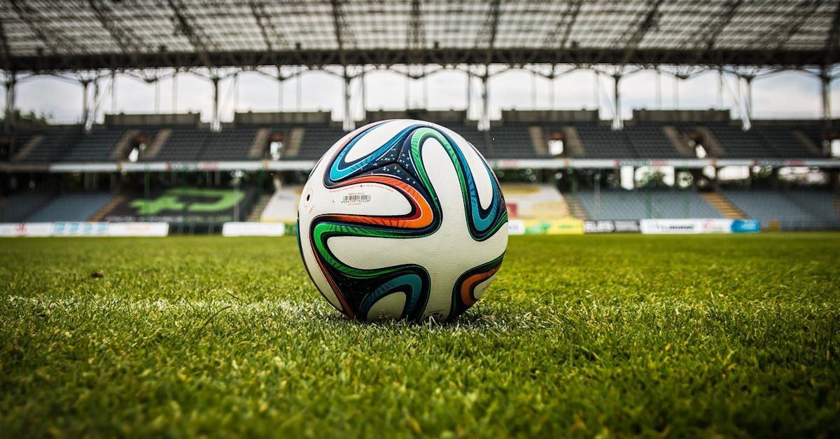 A soccer ball is sitting on the grass in a stadium.