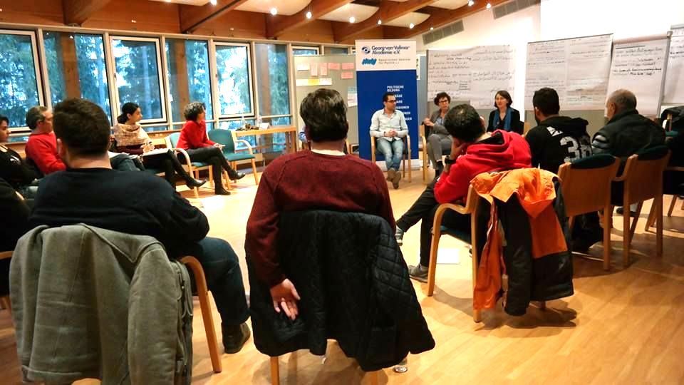 Teilnehmende sitzen im Kreis und diskutieren - Perspektive von der anderen Seite als beim ersten Foto