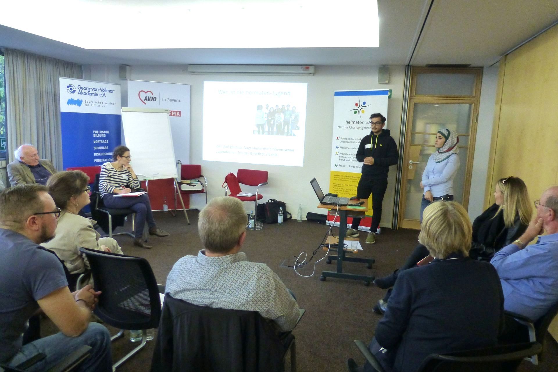 Plakate und Power-Point-Präsentation - erklärt von 2 Mitgliedern der heimaten-Jugend - Teilnehmende des Workshops im Stuhlkreis