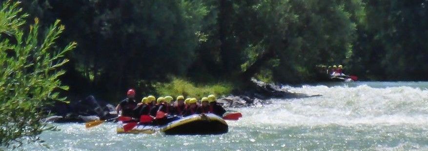 Rafting-Kanu auf der Isar mit vielen Jugendlichen und Wellengischt