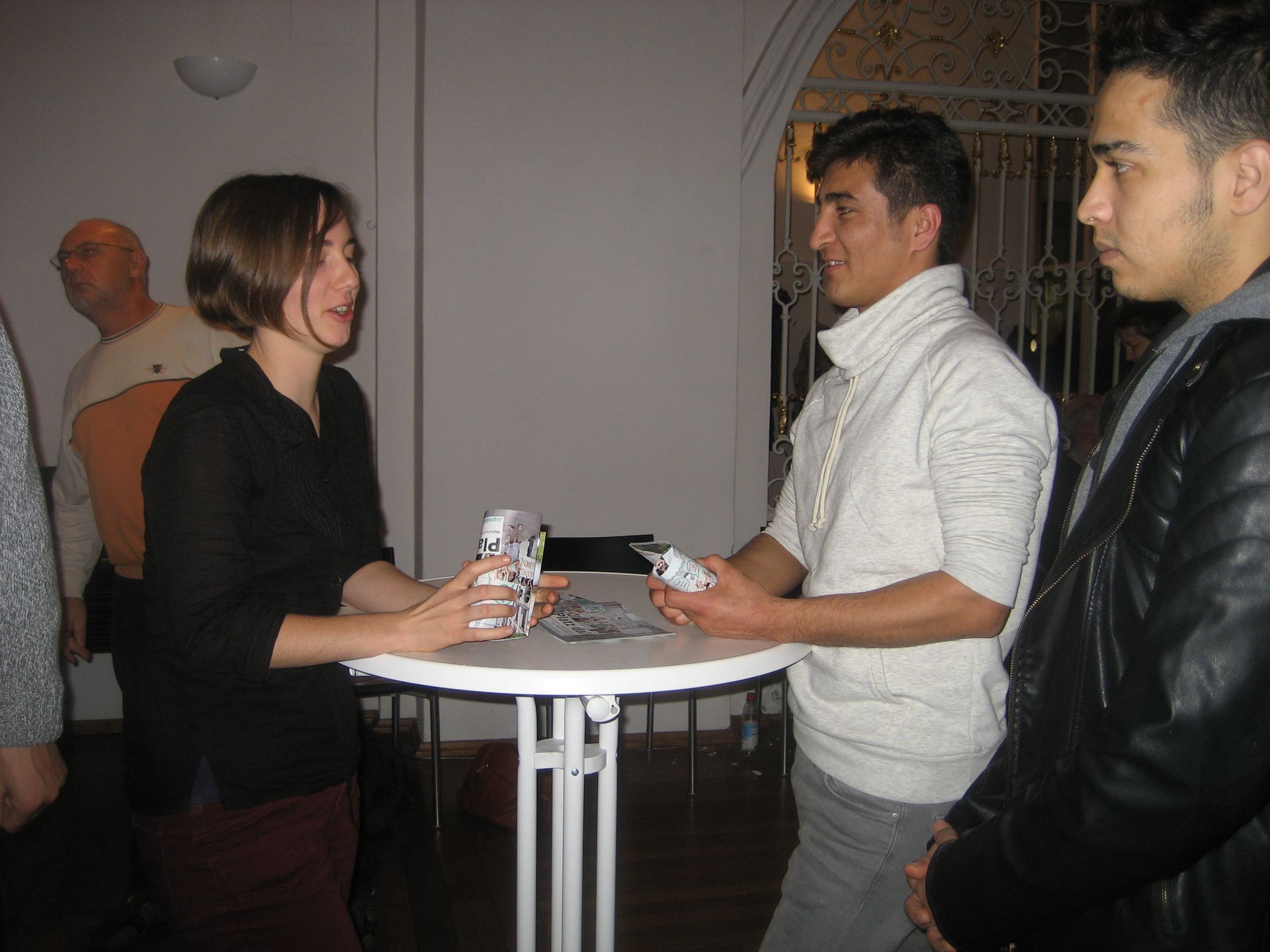 Junger Mann am Stehtisch mit anderen Teilnehmenden