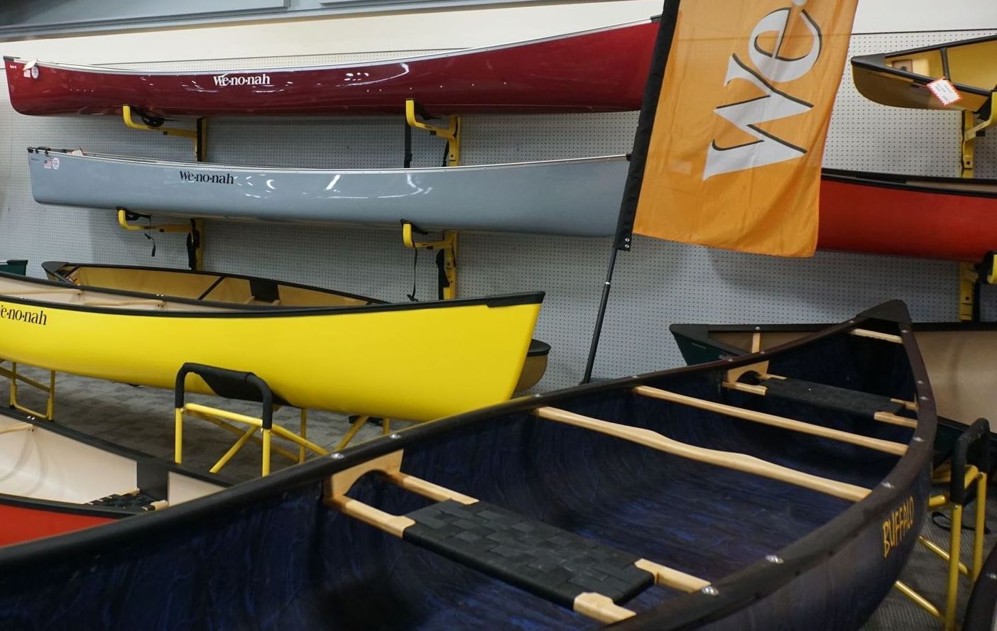 A row of canoes are lined up in a room with a flag that says wm on it