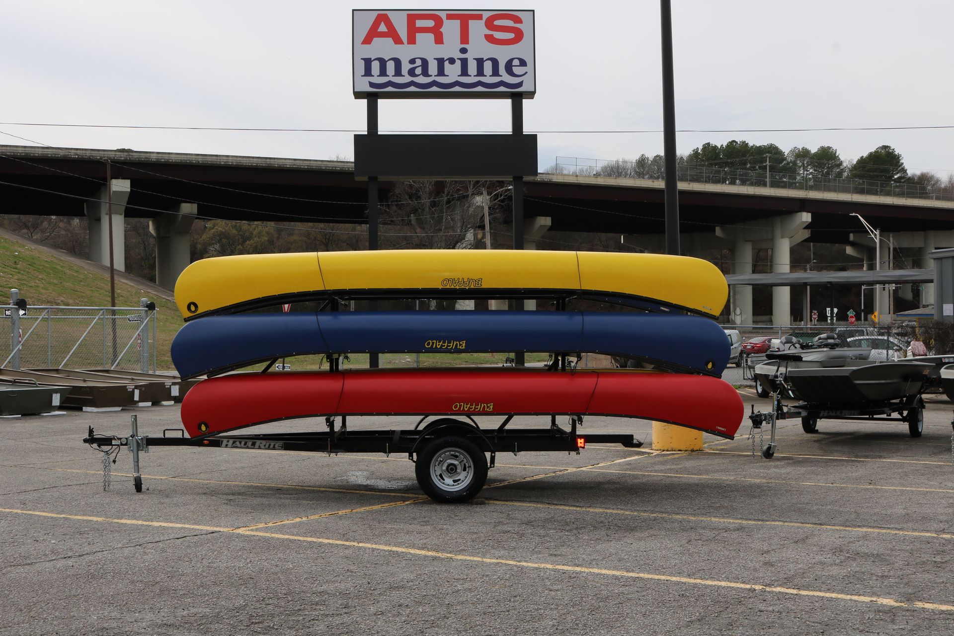 Three canoes on a trailer under a arts marine sign