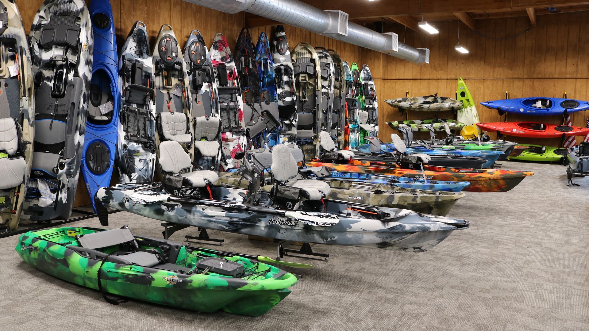 A row of kayaks are lined up in a room.