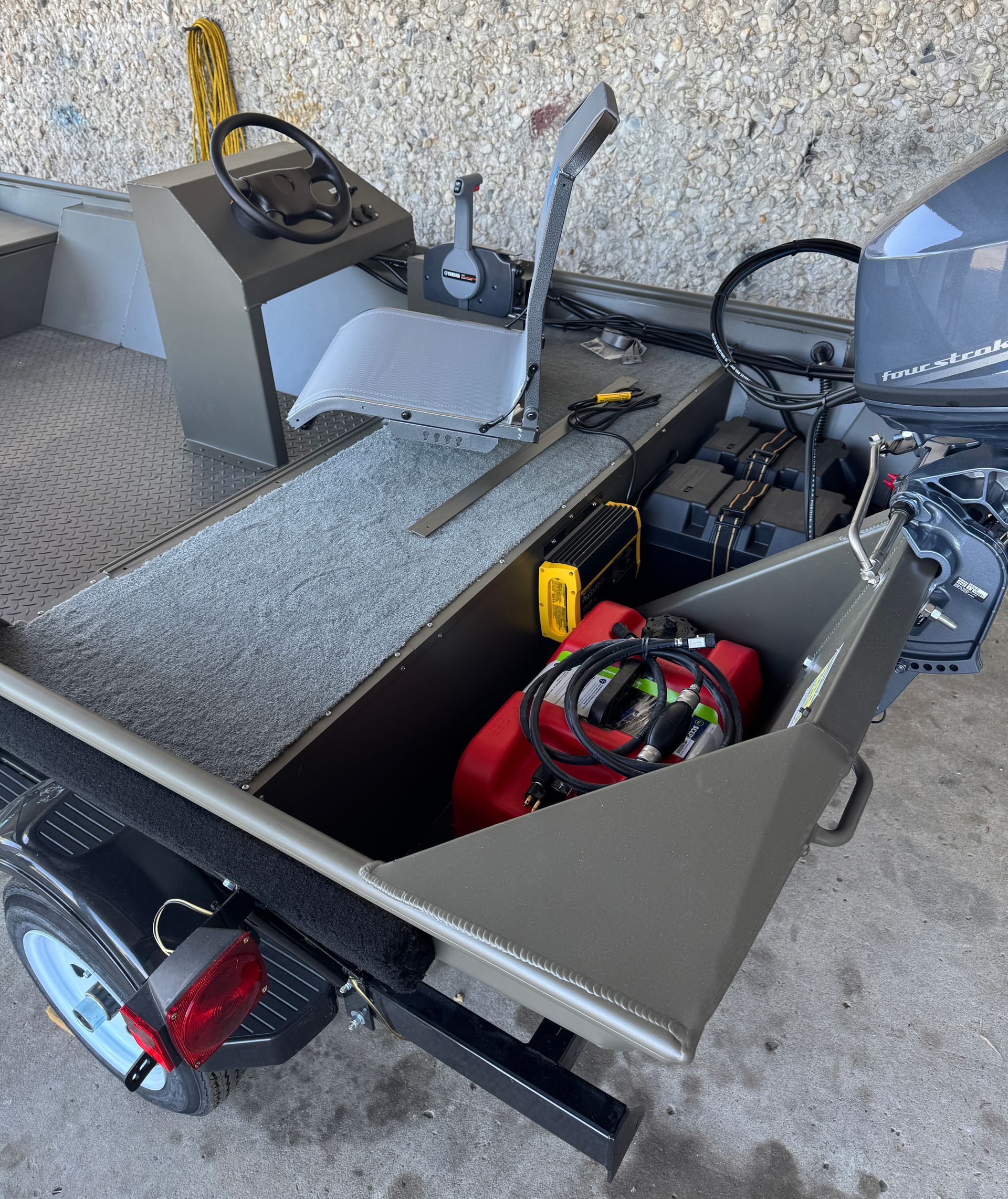 A boat with a gas tank in the back is parked in a garage.