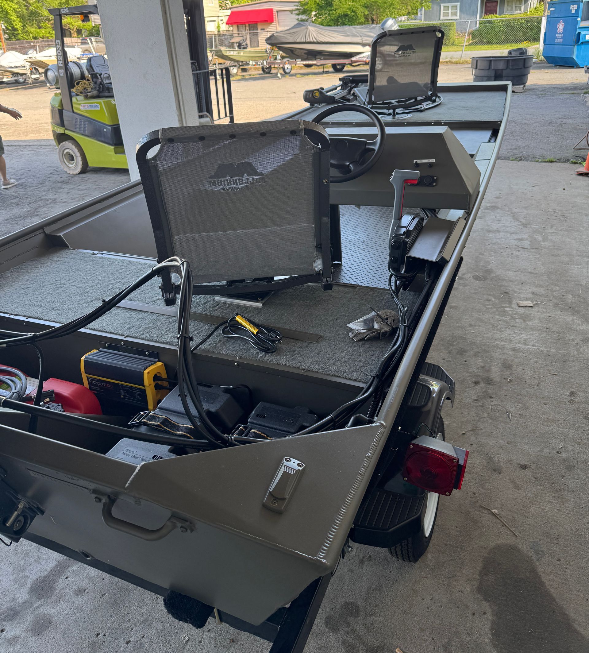 A boat is parked in a garage with a forklift in the background.