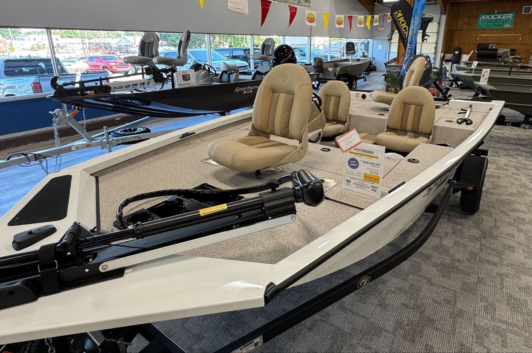 A white fishing boat is sitting in a showroom.