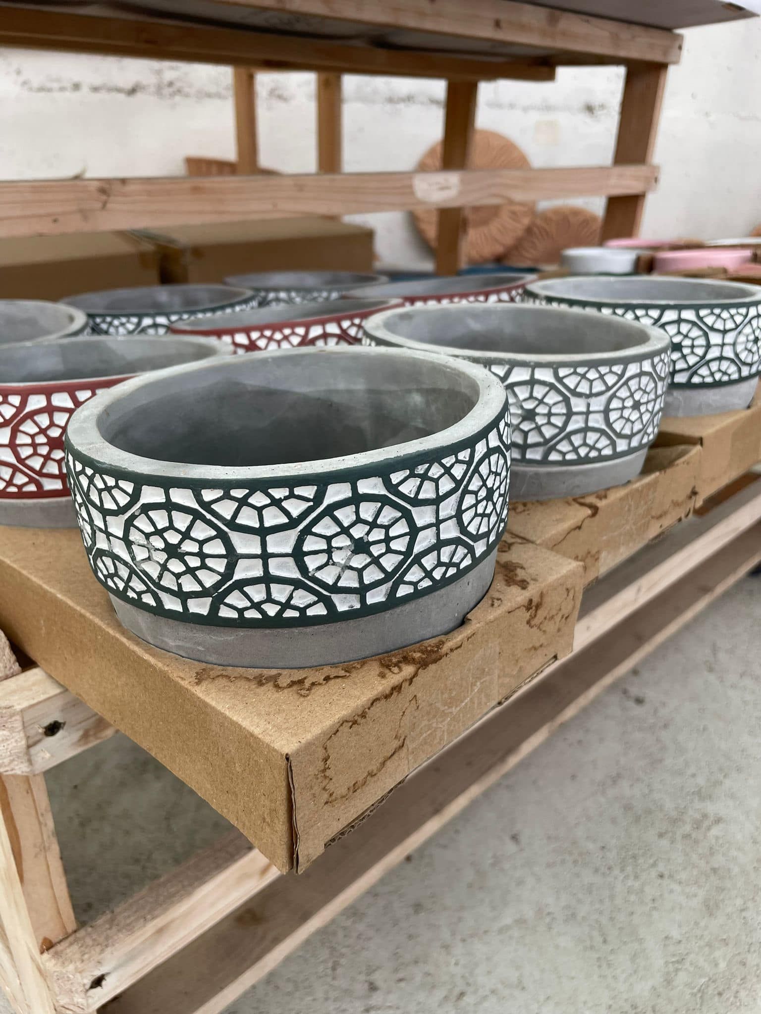Vasi in ceramica decorati a mano su scaffali di legno in un laboratorio.