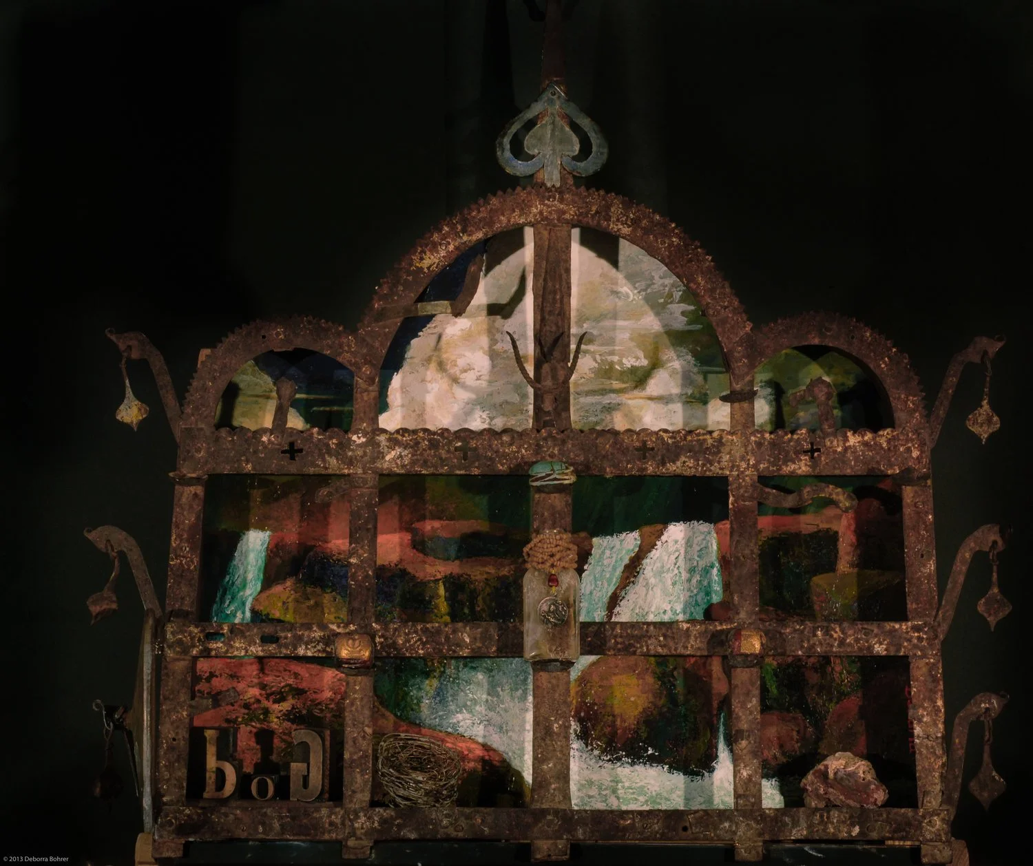 Ornate, rusty metalwork window frame with colorful abstract artwork visible through the glass panels.