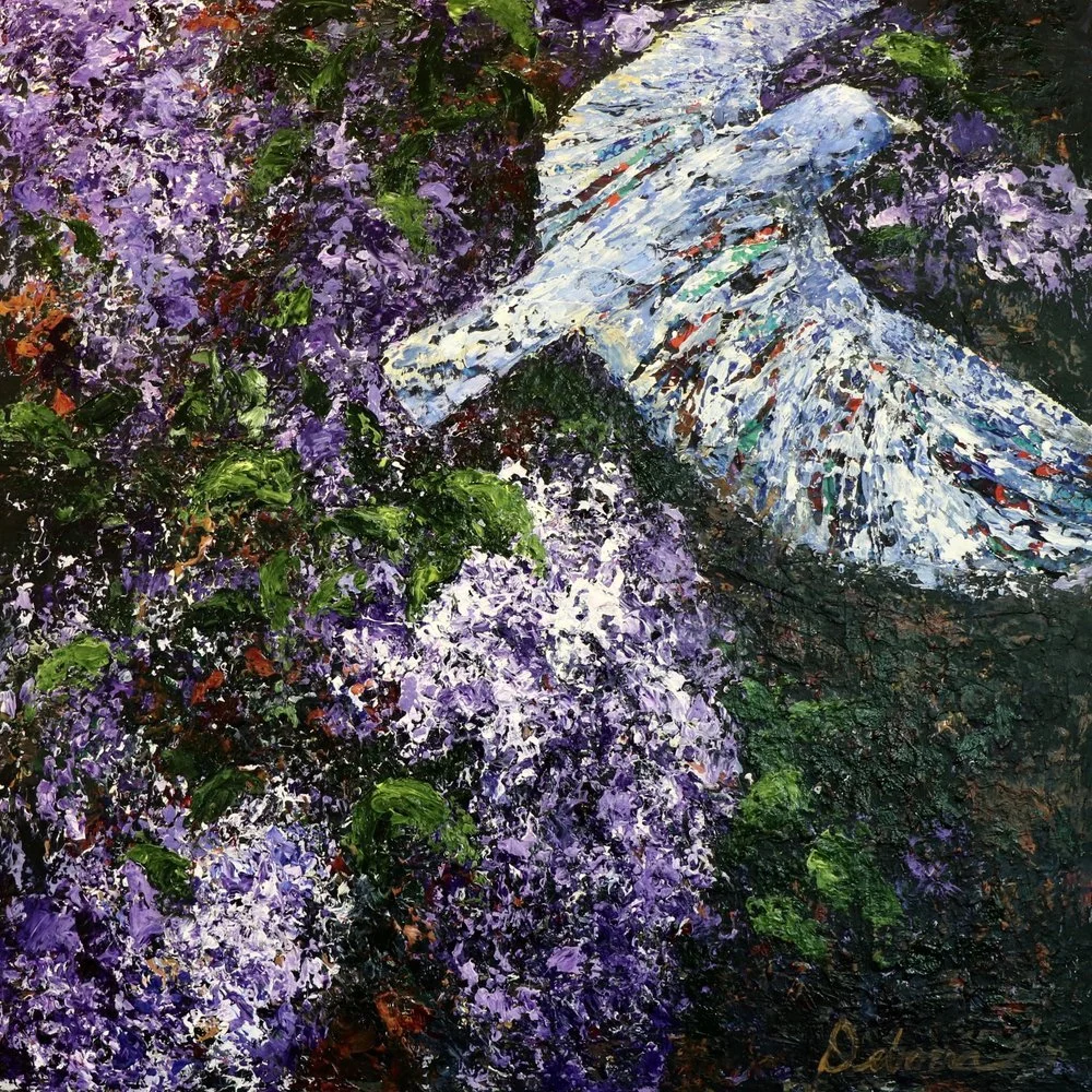 White bird flies through purple lilac blossoms.