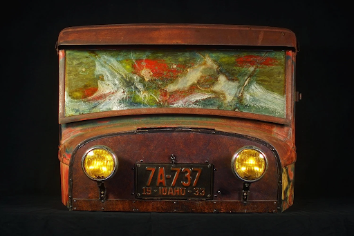 Metal sculpture of a truck front with Idaho license plate and landscape scene behind windshield.