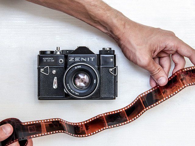 Camera on table with hands holding a film strip