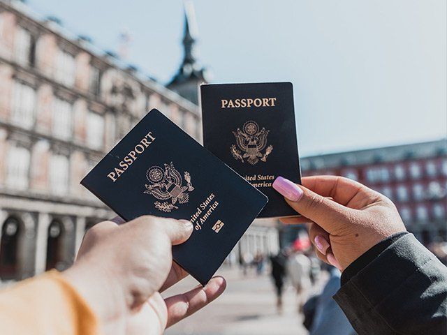 Hands holding two passports outside