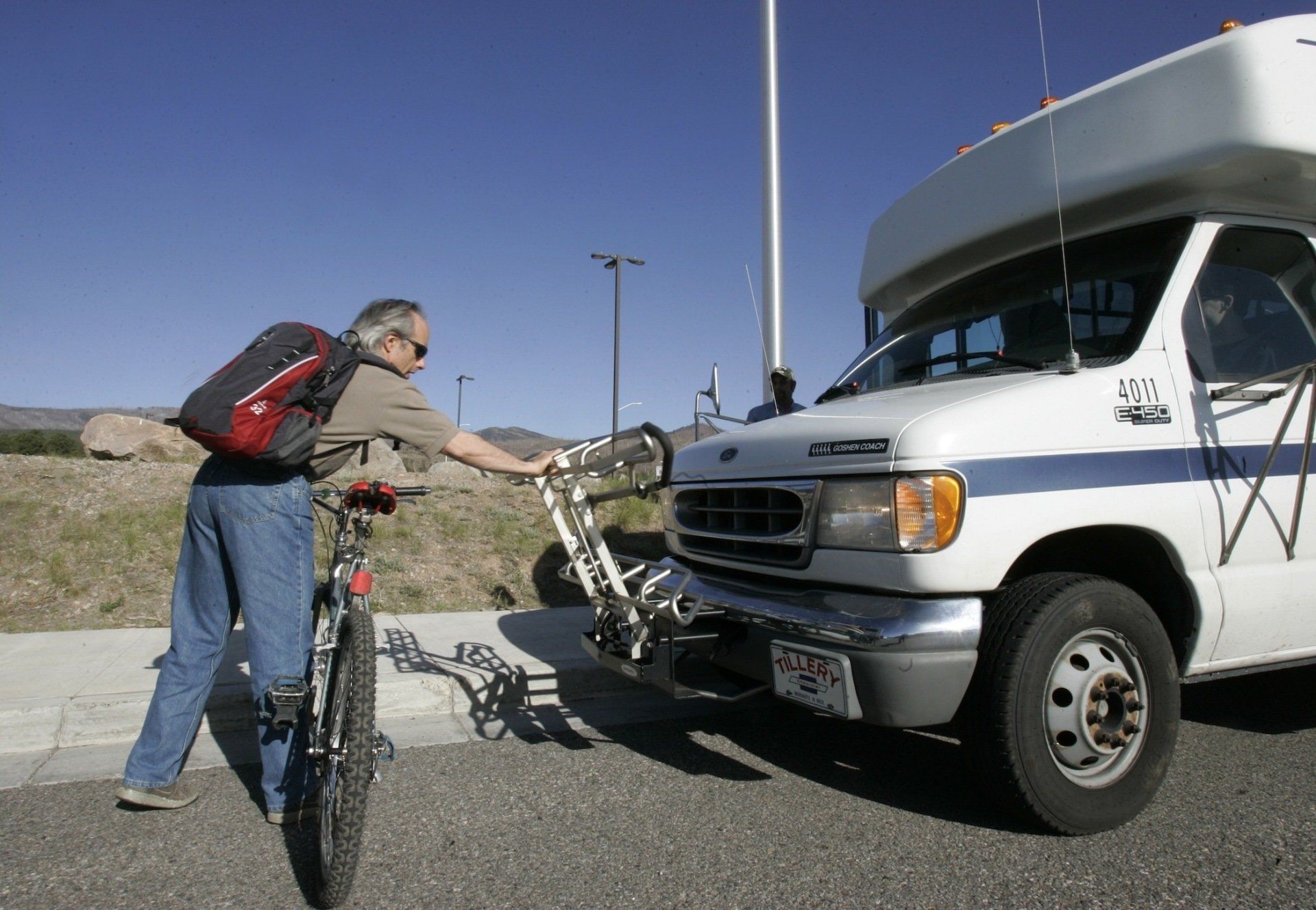 Passenger loading his bicycle on the front of bus