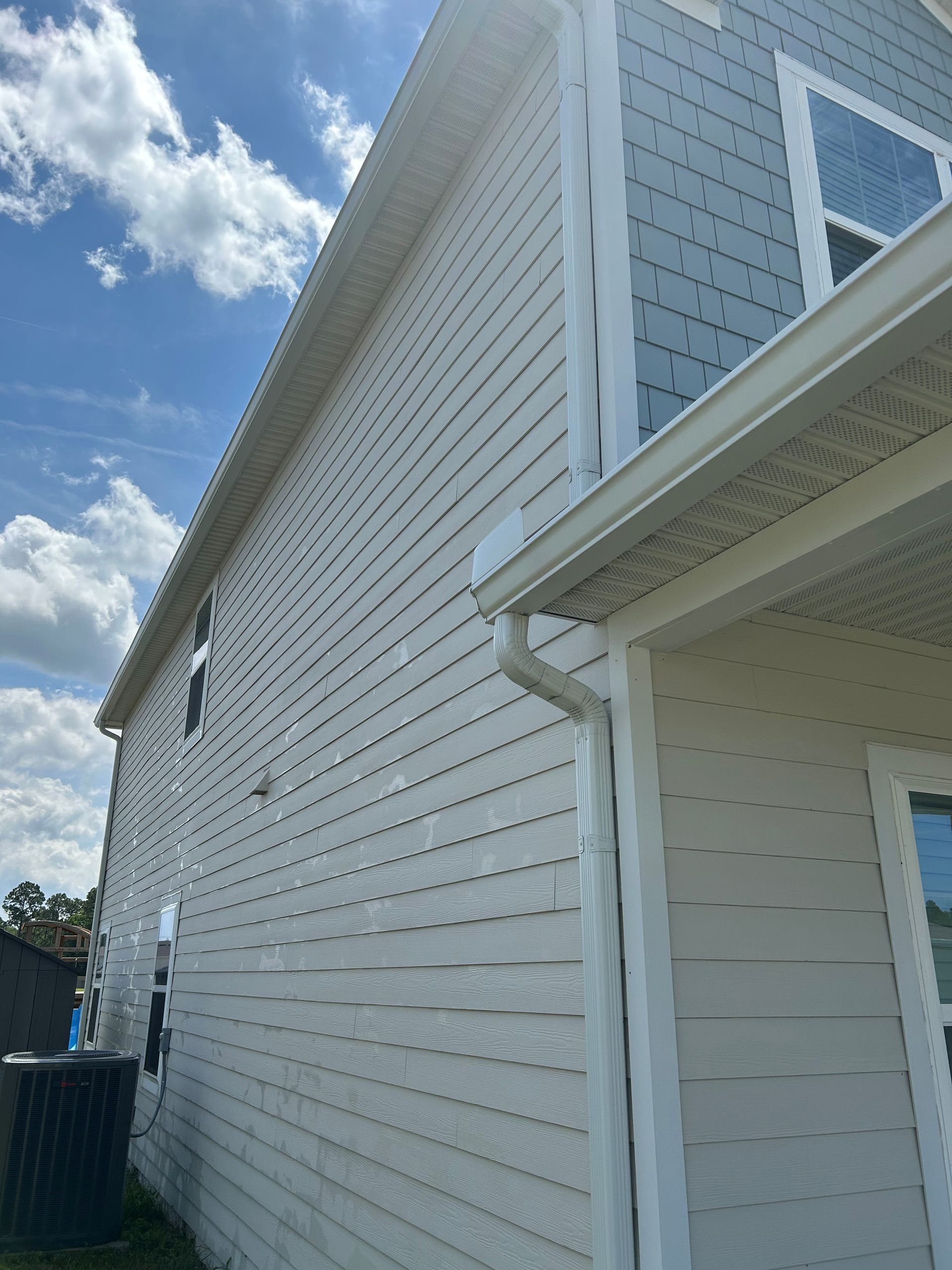 Gray porch ceiling with horizontal planks and supporting beams; a light green house exterior is visible below.