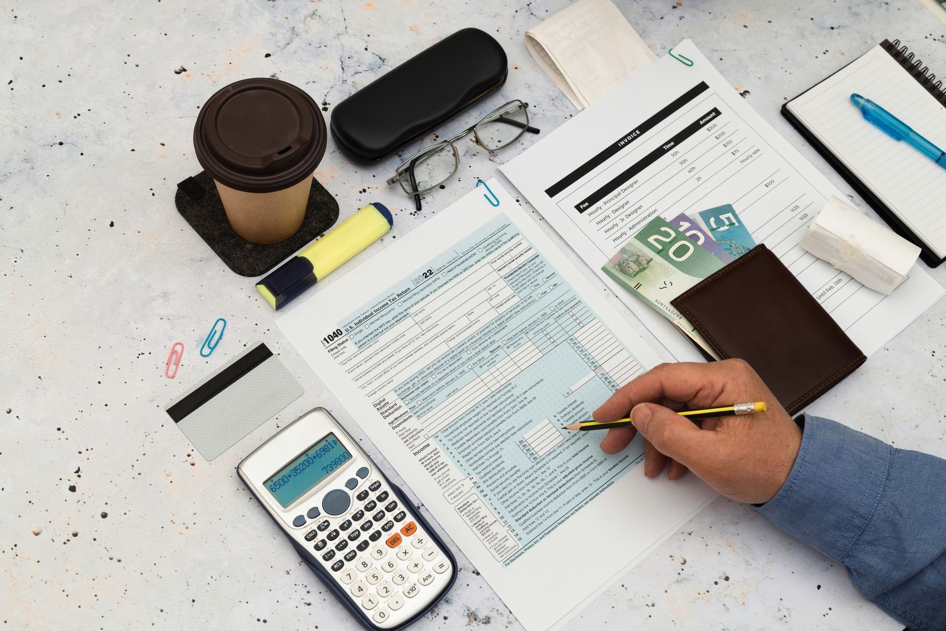 Two women at a desk reviewing documents with laptops, calculator, and pen, focused discussion.
