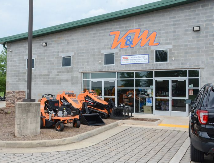Front entrance of K&M Lawn, Garden and Arborist Supplies in Culpeper, Virginia, featuring commercial lawn equipment and compact machinery on display.
